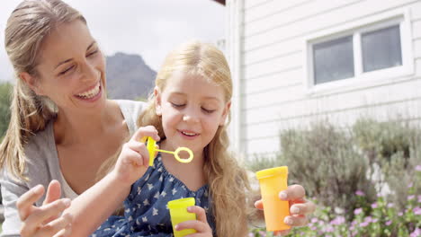 Madre-E-Hija-Soplando-Burbujas-En-El-Patio-Casa-Familiar-Feliz