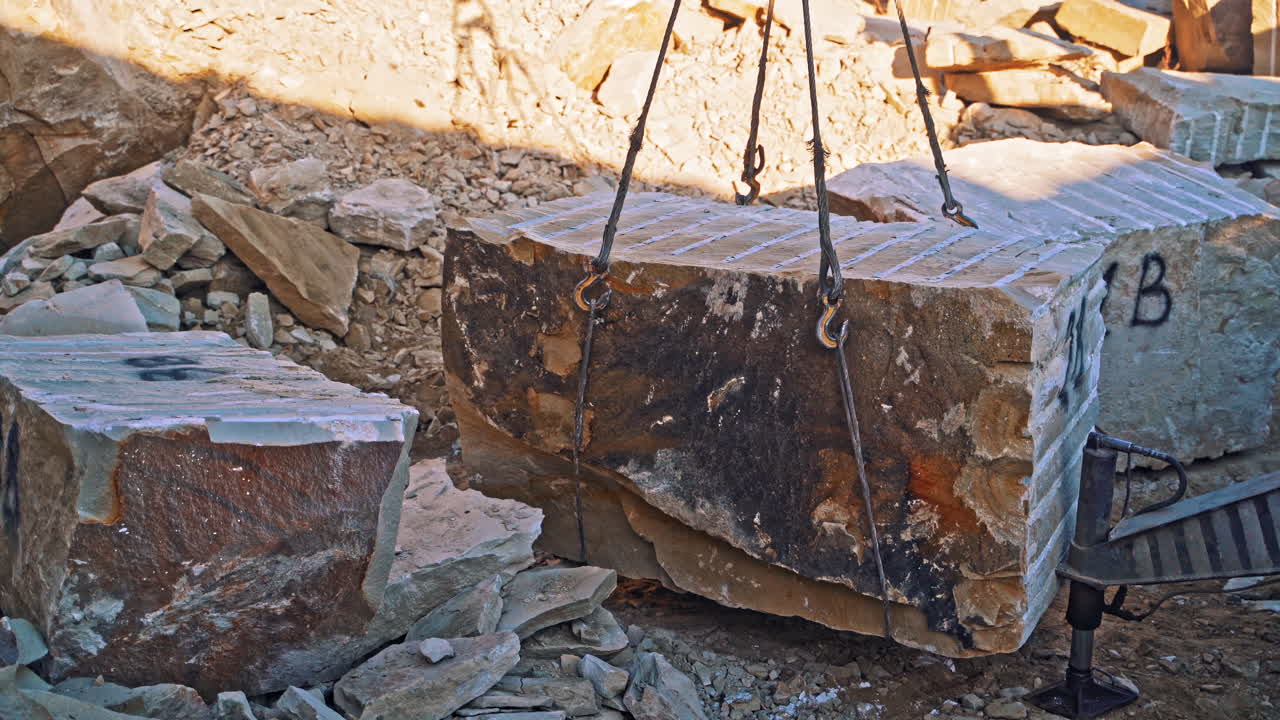 Crane lifting heavy rock. Heavy natural granite stone blocks stacked for processing
