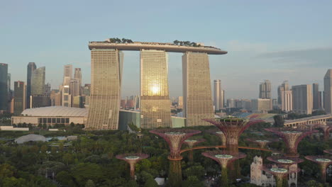 drone flight over gardens by the bay in singapore with view of marina bay sands hotel