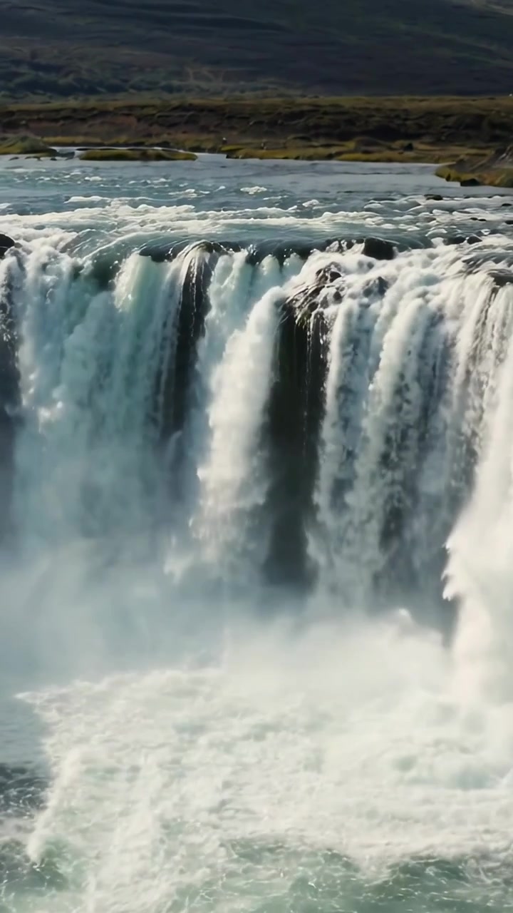 Video verticale: Acqua che trabocca dalla cresta del fiume formando tende alla cascata, creando nebbia e schiuma.