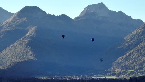 three hot air balloons taking off in a summer morning in the french alps