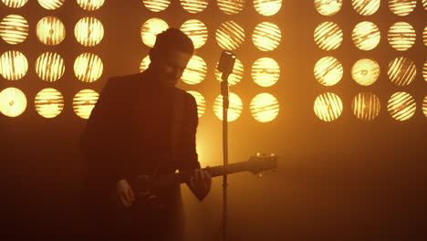 man singing microphone playing guitar on stage. guy performing song in club.