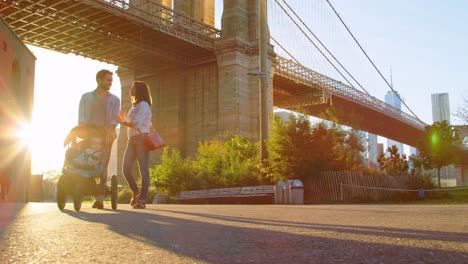 young family with stroller walking under bridge in manhattan