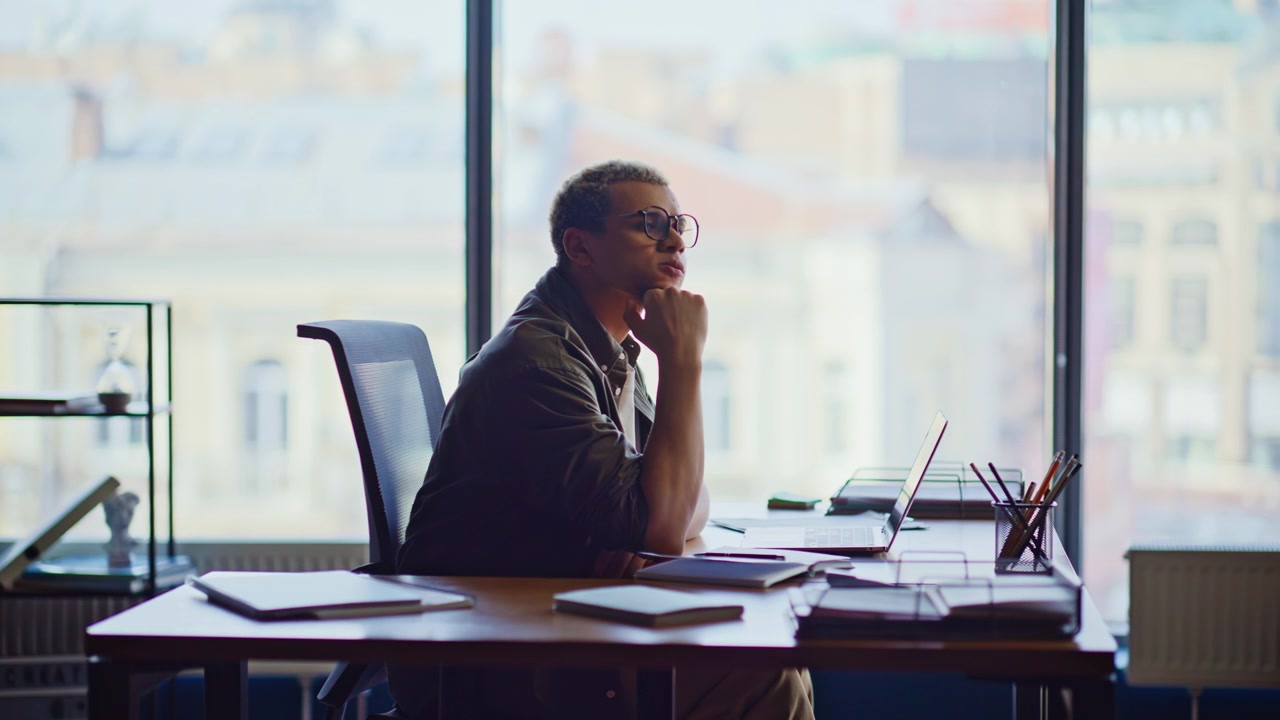 Young entrepreneur thinking at office desk. Man pondering business idea