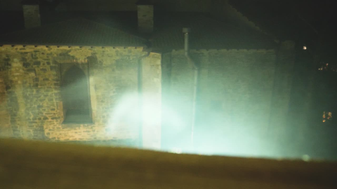 proyección de luz sobre el humo y una pared medieval en el fondo