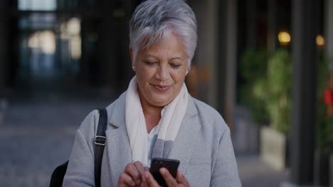 portrait senior indian business woman using smartphone enjoying texting browsing messages reading emails in city slow motion