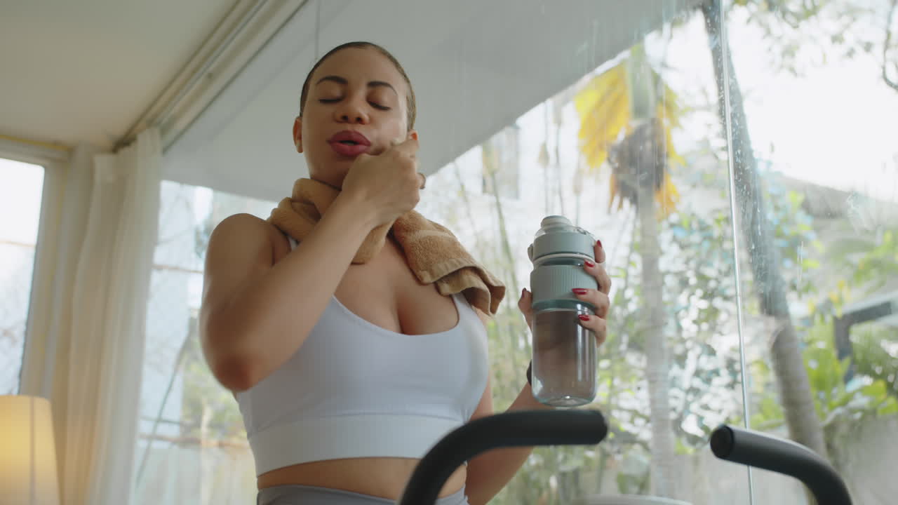 Young Sportswoman Having Drink after Workout Indoors