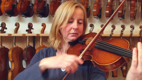 customer trying out violin in music store