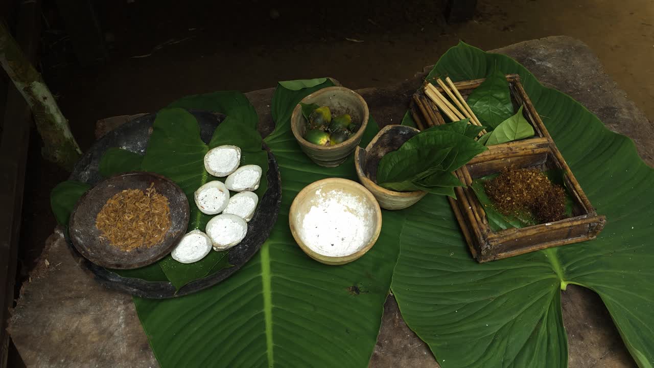Various traditional food ingredients, including white slices, powder, and fruits, are laid out on green leaves during a preparation demonstration in Mari Mari village, Kota Kinabalu, Malaysia