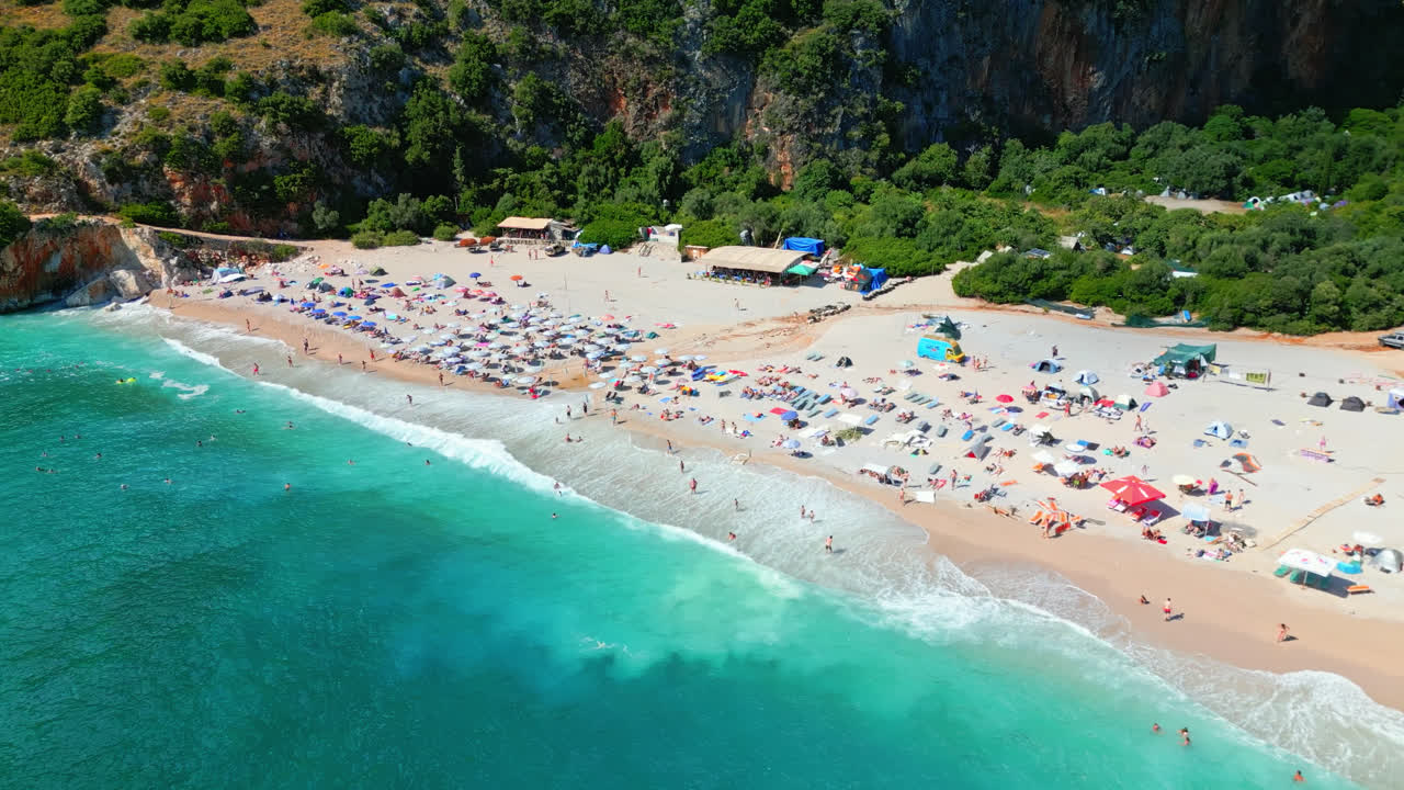 Aerial drone top down shot over tourists sunbathing on secluded Gjipe beach, Albania on a bright sunny day