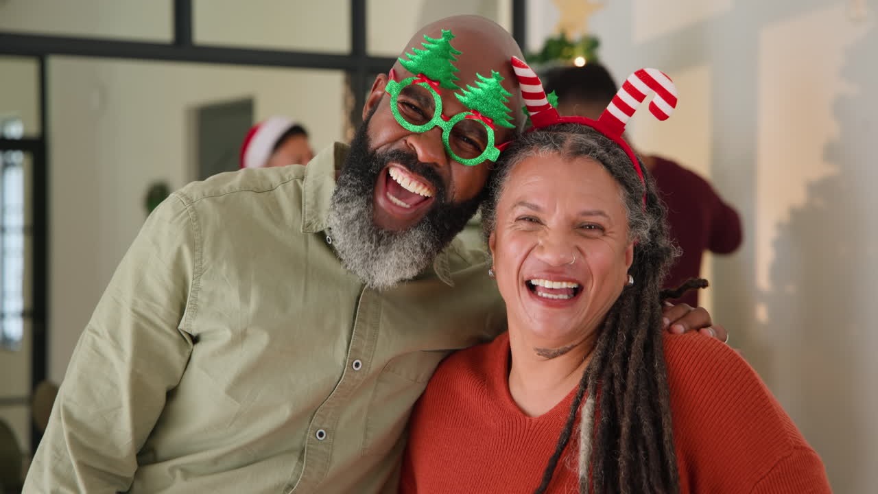 Celebrating Christmas at home, joyful couple wearing festive accessories, smiling together