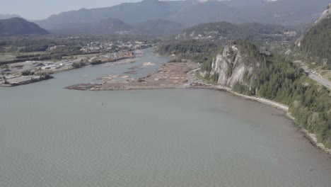 Vuelo-Aéreo-Sobre-El-Puerto-De-La-Bahía-Mineral-Del-Océano-De-La-Industria-Maderera-Muelle-De-Exportación-De-Inventario-Apilado-Para-La-Preparación-Para-Abordar-Remolcadores-Al-Puerto-De-Transporte-De-Carga-En-Un-Día-Claro-De-Verano-1-4