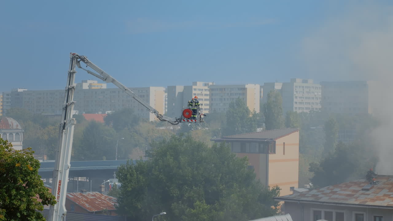 Пожарные на автолестнице поднимаются на крышу горящего дома