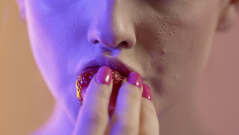 close up of woman's face and mouth eating chewing strawberry fruit, studio shot