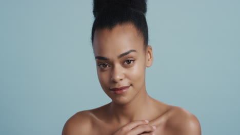 portrait beautiful african american woman touching smooth healthy skin with hand attractive girl with soft complexion enjoying perfect natural beauty on blue background