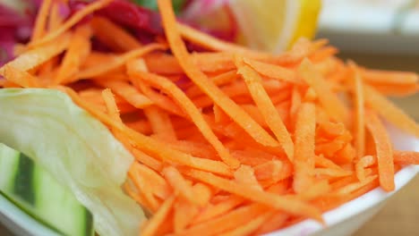 un primer plano de una ensalada con zanahorias trituradas, lechuga y pepino.