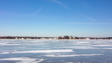 plano amplio de un amplio río congelado con un velero de hielo navegando alrededor