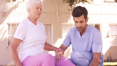 male nurse assisting senior woman to exercise in the backyard