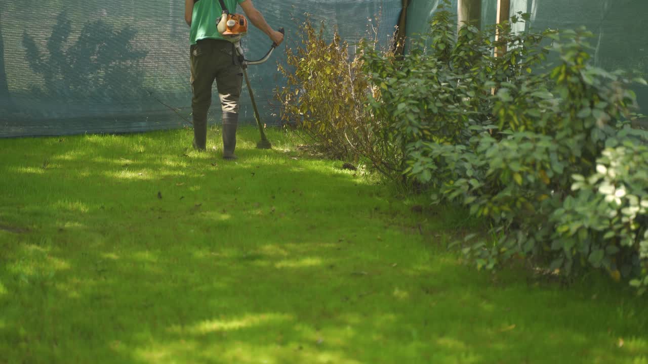 브러시 커터 전기로 녹색 잔디를 다듬는 인식할 수 없는 남자