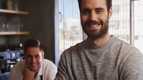 Portrait-of-man-standing-with-arms-crossed-at-counter