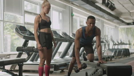 Front-view-of-caucasian-female-monitor-and-an-athletic-african-american-man-in-the-gym.