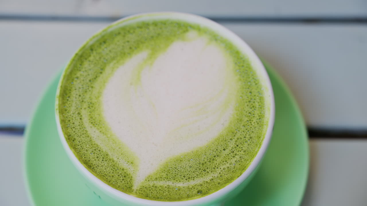 Close up of a matcha latte in a green cup on a terrace table