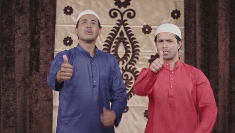 two muslim men showing thumbs up to the camera