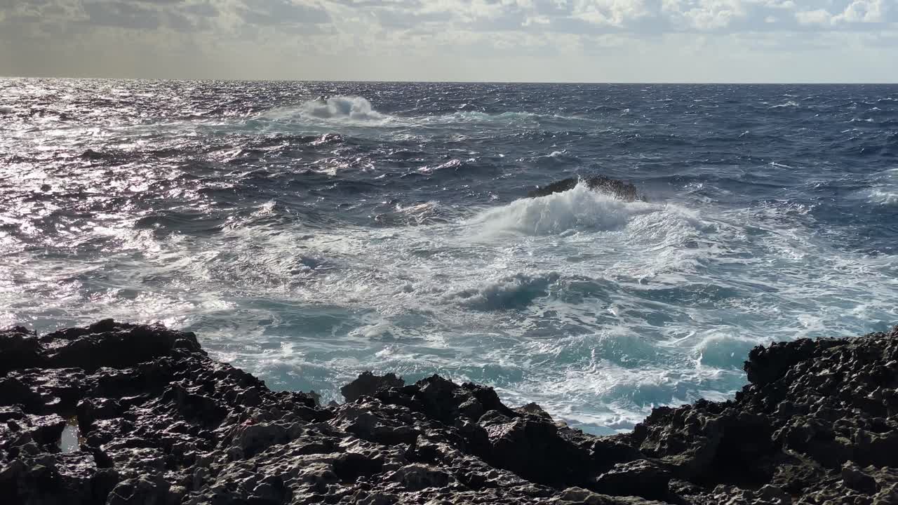 Onde si infrangono e ribollono mentre il mare sferza la costa rocciosa maltese, al rallentatore