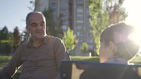 abuelo y nieto charlando al aire libre en un día soleado.