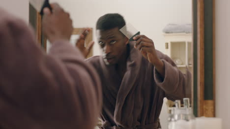 happy african american man dancing in bathroom looking in mirror having fun morning routine getting ready enjoying positive self image wearing bathrobe