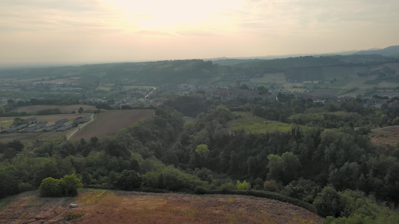 la puesta de sol sobre una pintoresca ciudad enclavada en un valle, proyectando largas sombras sobre colinas y campos, creando una atmósfera serena en la provincia italiana de piacenza.