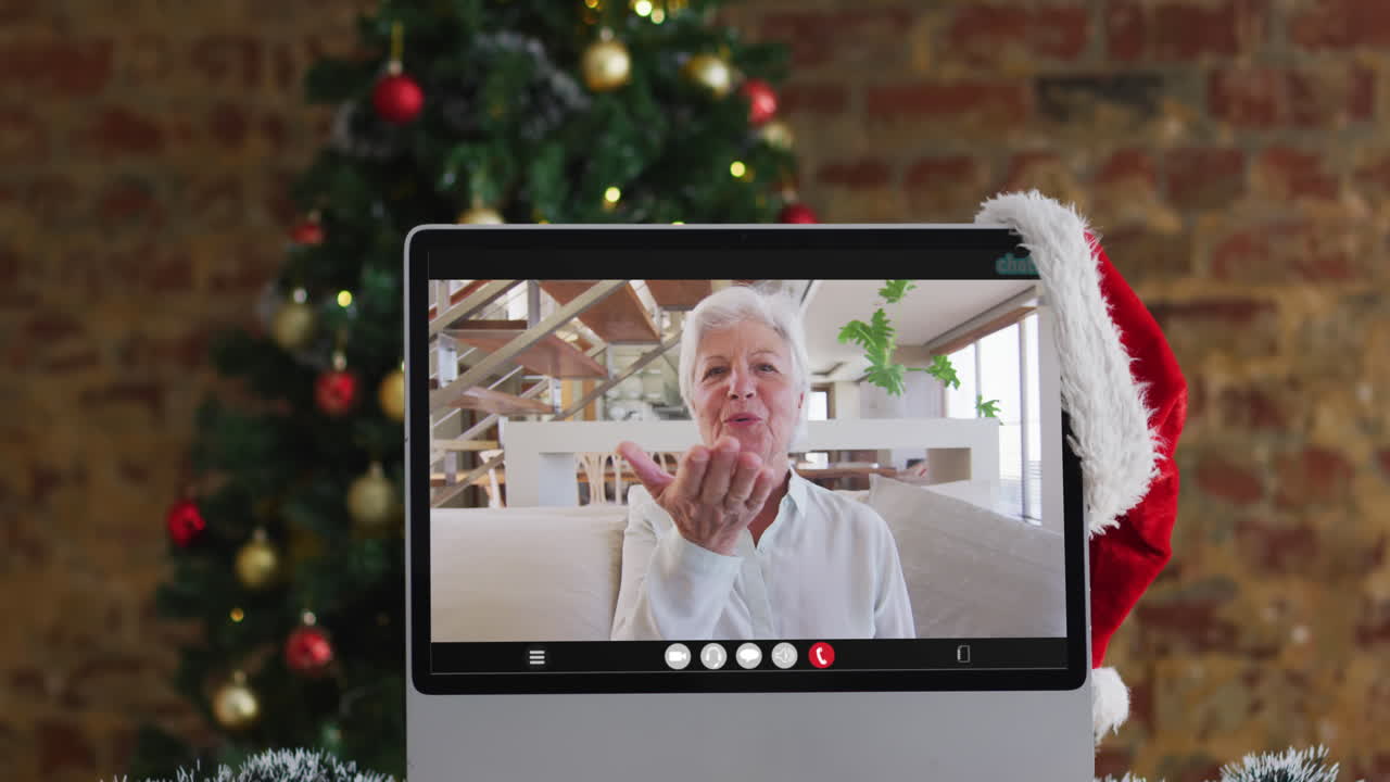 mujer mayor caucásica feliz en videollamada en el monitor de la computadora, con árbol de navidad