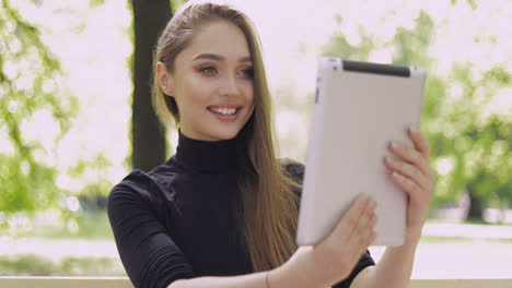 Young-smiling-woman-using-tablet-for-online-conversation