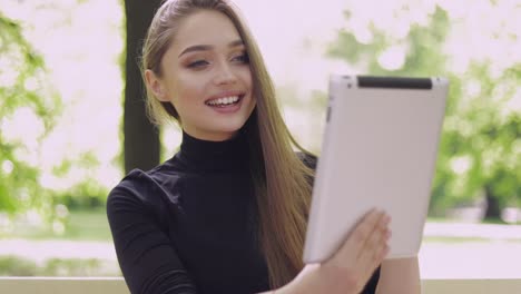 young smiling woman using tablet for online conversation