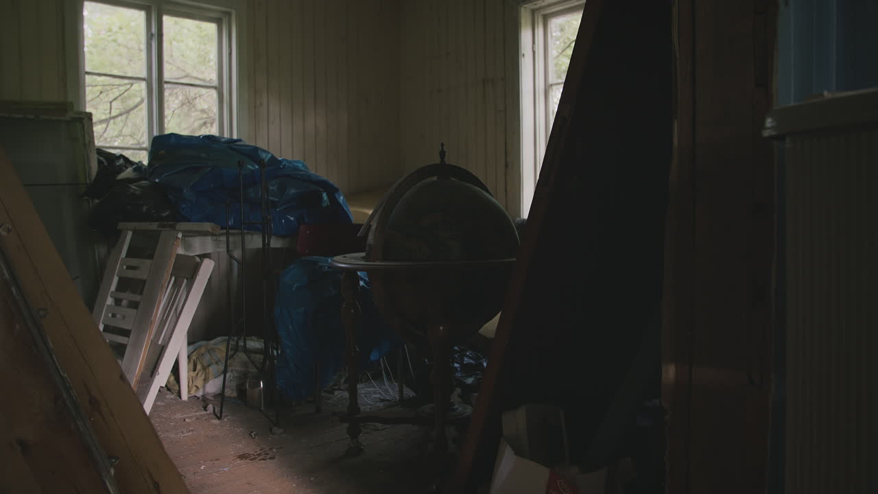 Dimly lit room with wood-paneled walls, a vintage globe, and various items piled together.