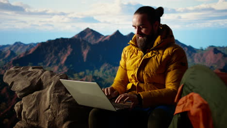 tech savvy hiker having a technology obsession and working on a mountain peak