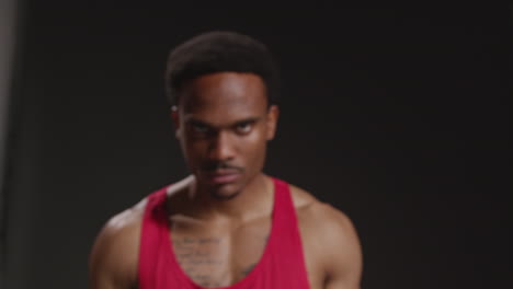 Close-Up-Portrait-Of-Serious-Male-Boxer-Wearing-Vest-Walking-Towards-Camera-And-Snarling-Training-Against-Black-Studio-Background