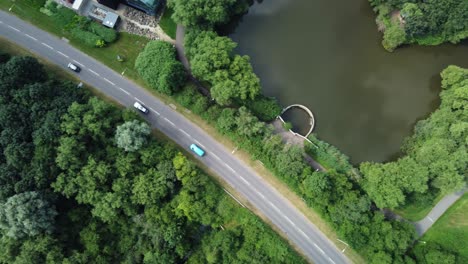 Aerial-view-over-road,-forest-and-lake,-slowly-flying-right-to-left