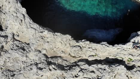 Aerial-forward-top-view-of-Coral-Lagoon-Cave-in-Armier-Bay-in-Mellieha,-Malta