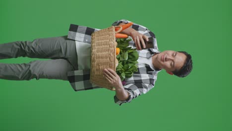hombre sosteniendo una canasta de verduras y usando un teléfono
