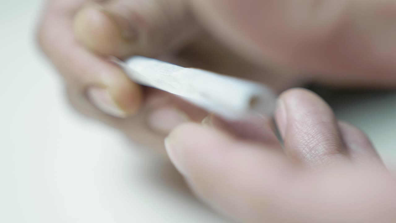 PRIMO PIANO: Mani maschili che arrotolano una sigaretta di cannabis terapeutica.