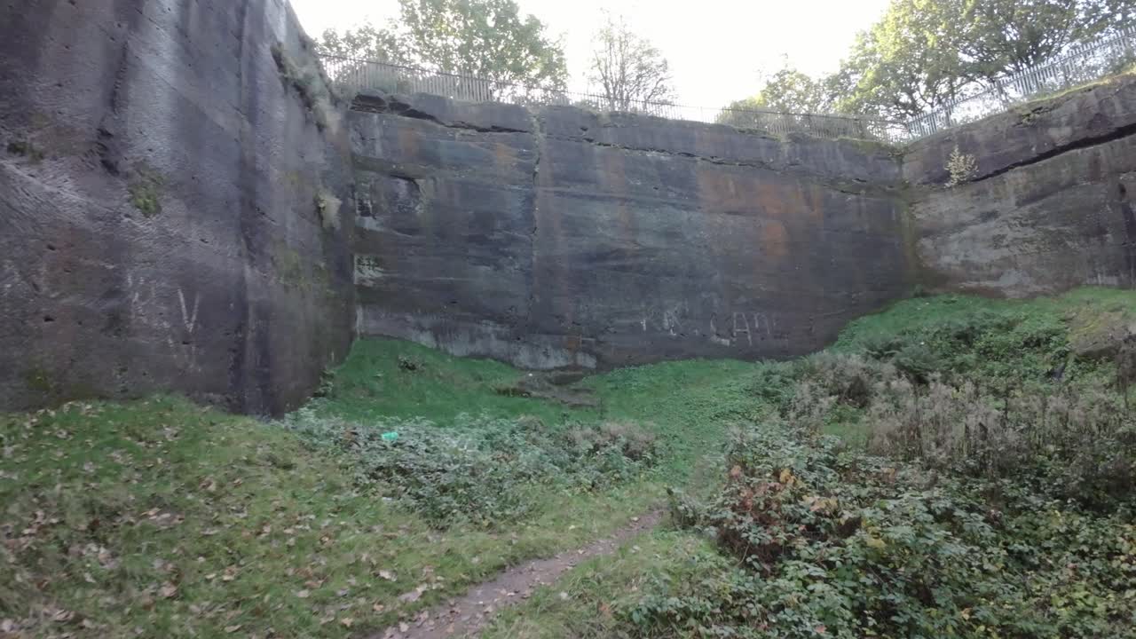 fpv drone tejiendo a través de un denso bosque de canteras de piedra con la luz del sol brillando a través de los árboles y el follaje