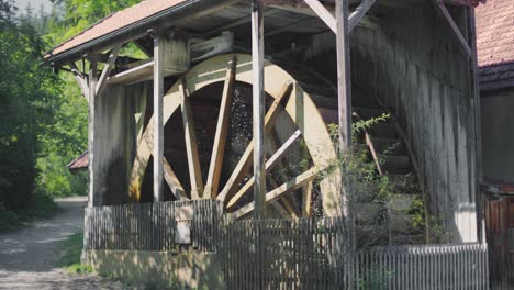 slow motion close up of a gigantic historic ancient wooden water wheel of a watermill spinning while water is flowing on it, splashing it around