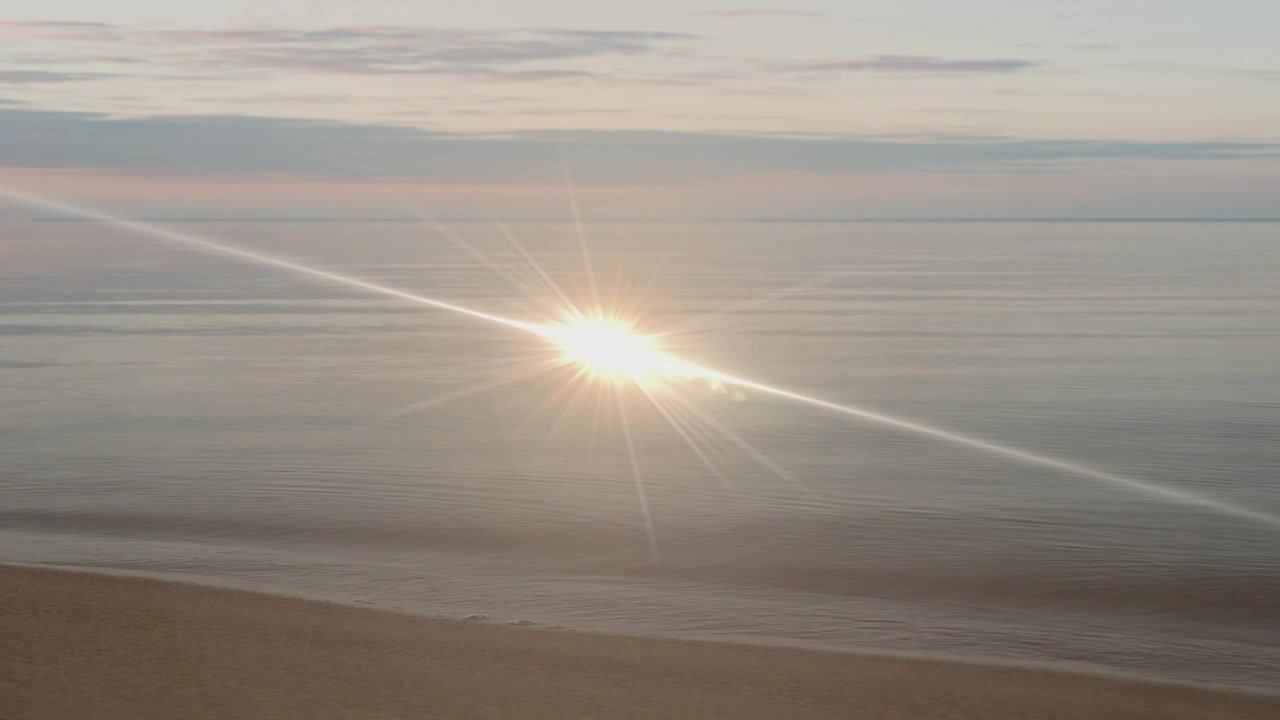 Light beam appearing at left creating starburst flare crossing sea fading into sunlight effect