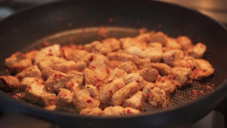 seasoned chicken chunks being fried in saucepan