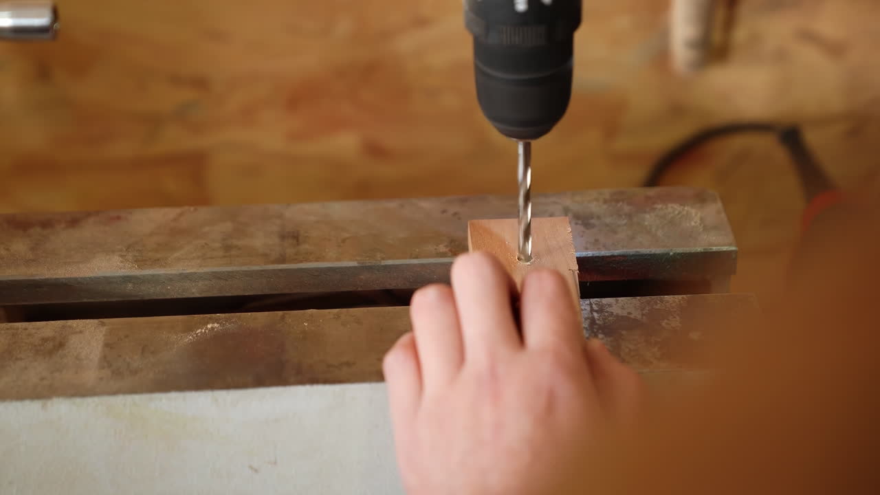 Carpinteros expertos, artesano ebanista en un taller con un bloque de madera, perforando un agujero en un tablón de madera con un taladro eléctrico a batería. Profesional de la carpintería en taller de montaje.