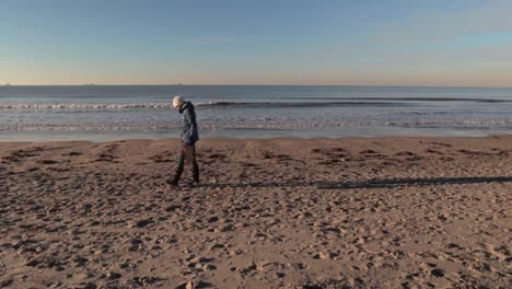 Young-woman-picking-up-trash-at-beach