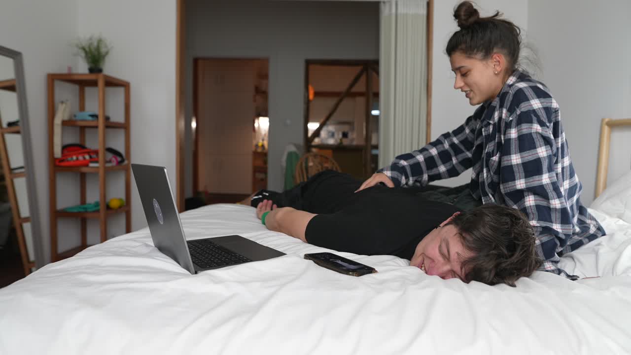Couple relaxing in bedroom, one is sleeping on bed