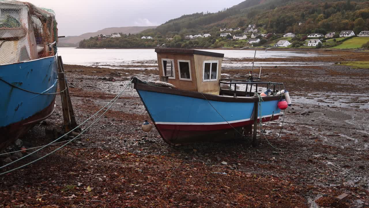 barcos de pesca en la playa rocosa de arena negra de portree en la isla de skye, tierras altas de escocia