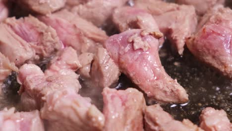 chunks of fresh meat are fried in a pan with butter.